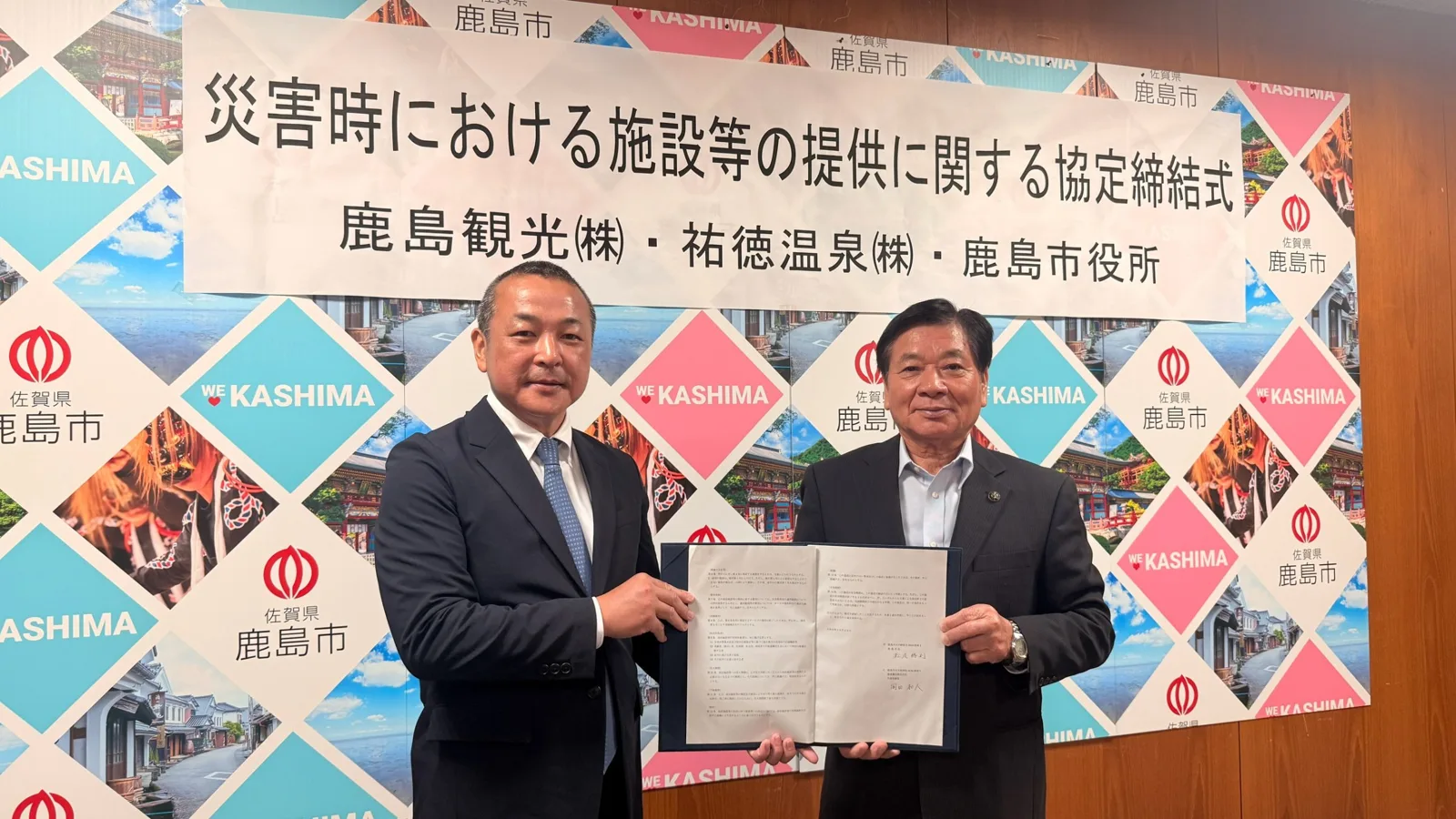 災害時における施設等の提供に関する協定締結式で協定書を掲げる様子